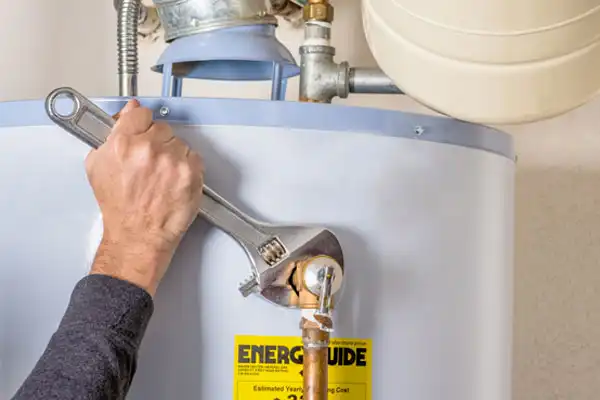 Person using a wrench to tighten a pipe on a water heater.